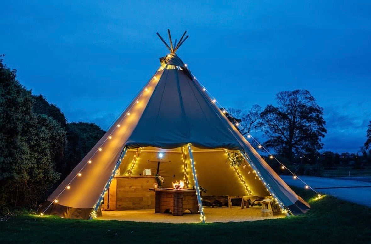 Single tipi illuminated at dusk with its entrance open